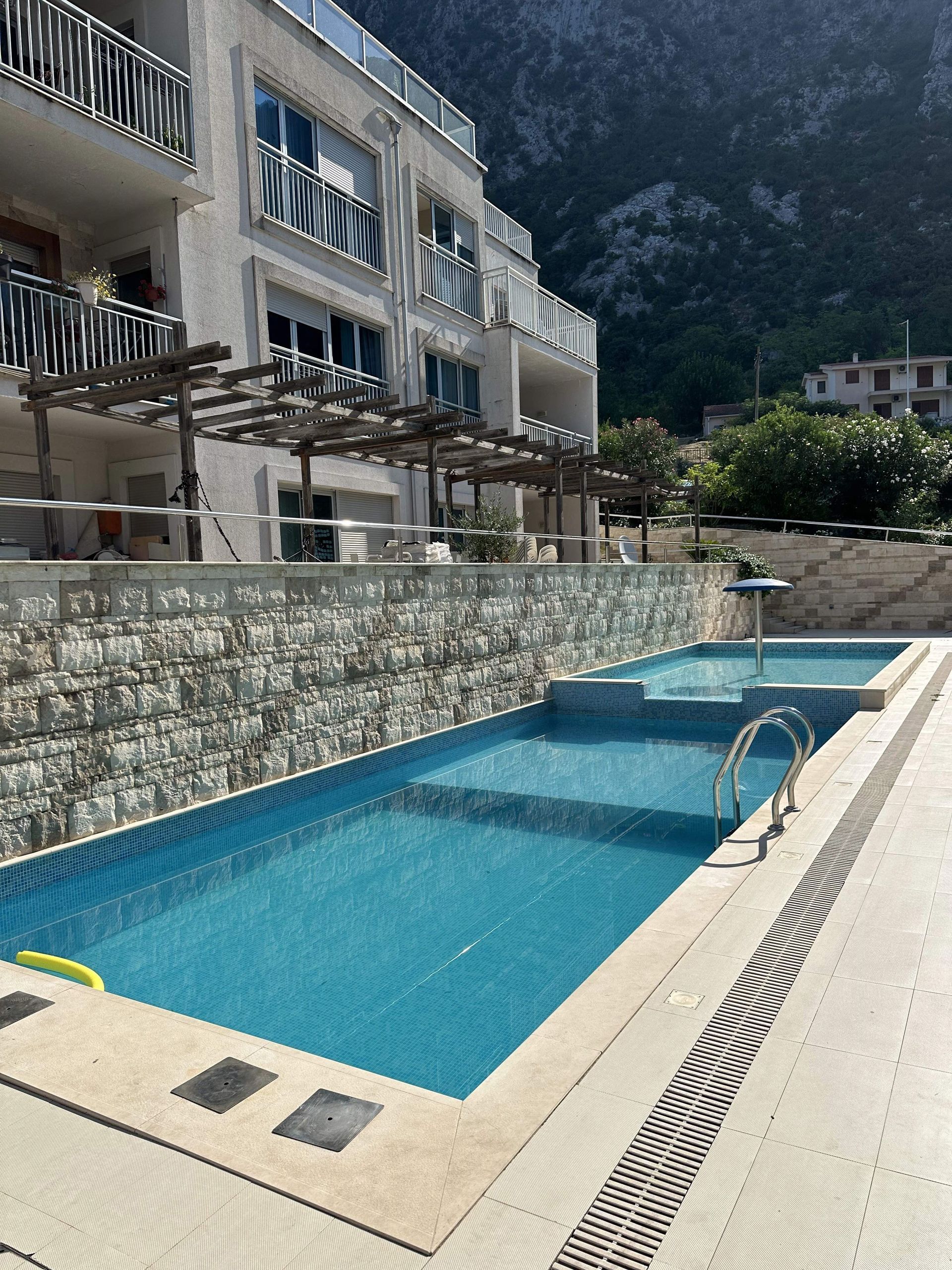 amforaproperty.com/Dvosoban Stan sa Pogledom na More u Kompleksu sa Tri Bazena i Privatnim Parking Mestom – Dobrota, Kotor